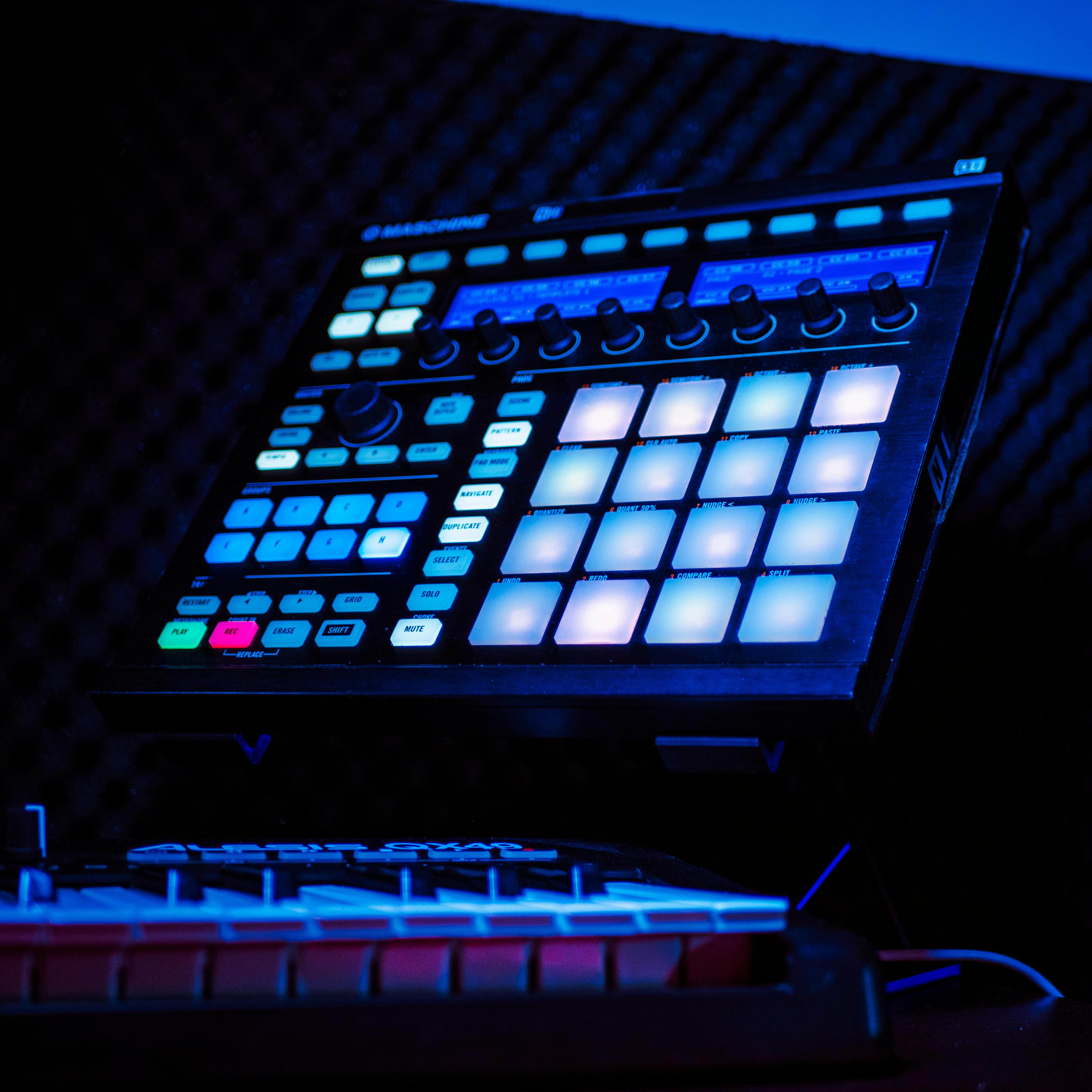 Close-up of an illuminated music production controller with colorful pads in a studio setting.